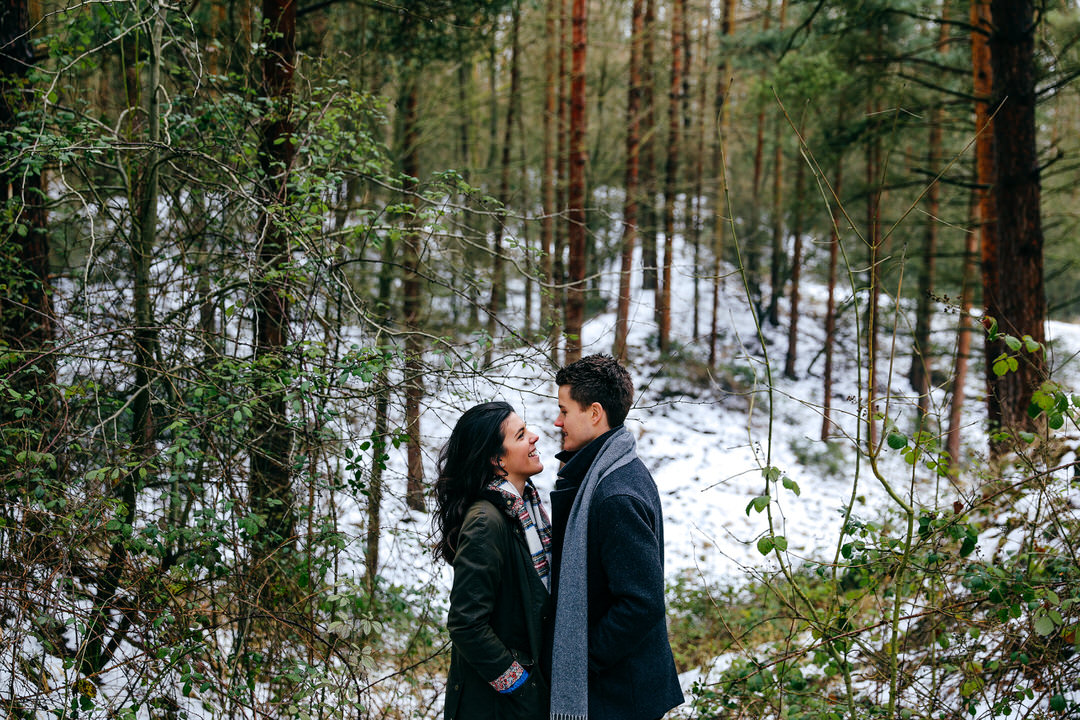 Couple facing each other in pine forest having a chat during their engagement shoot in Northamptonshire 